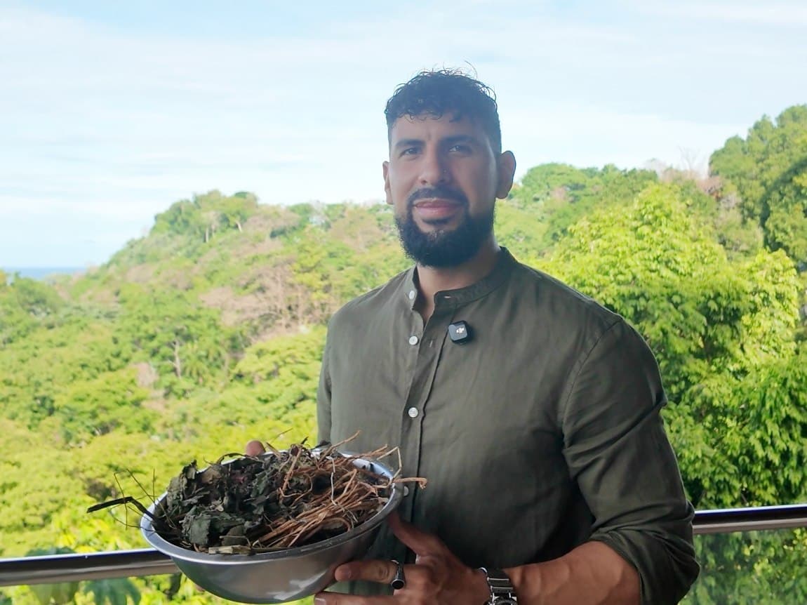 Chris holding a bowl of dried herbs, jungle behind him